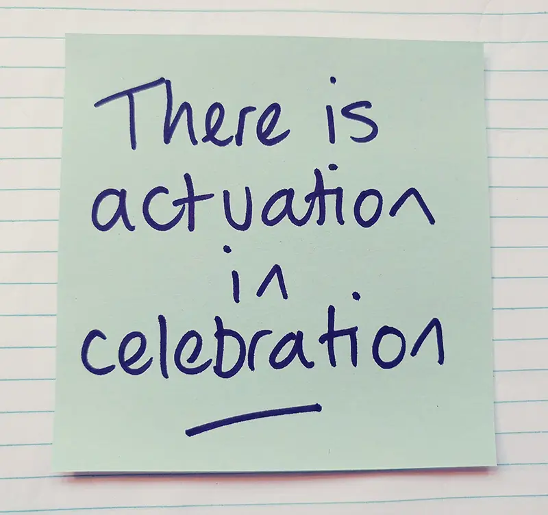 A post-it note with the words "There is actuation in celebration" written on it.