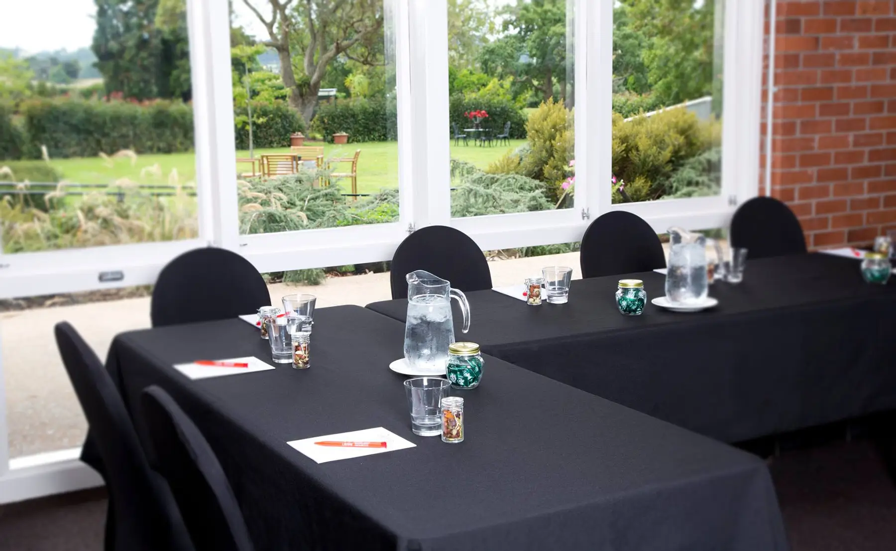 Carafes of water and notebooks are set up on cloth-covered tables, ready for a workshop.