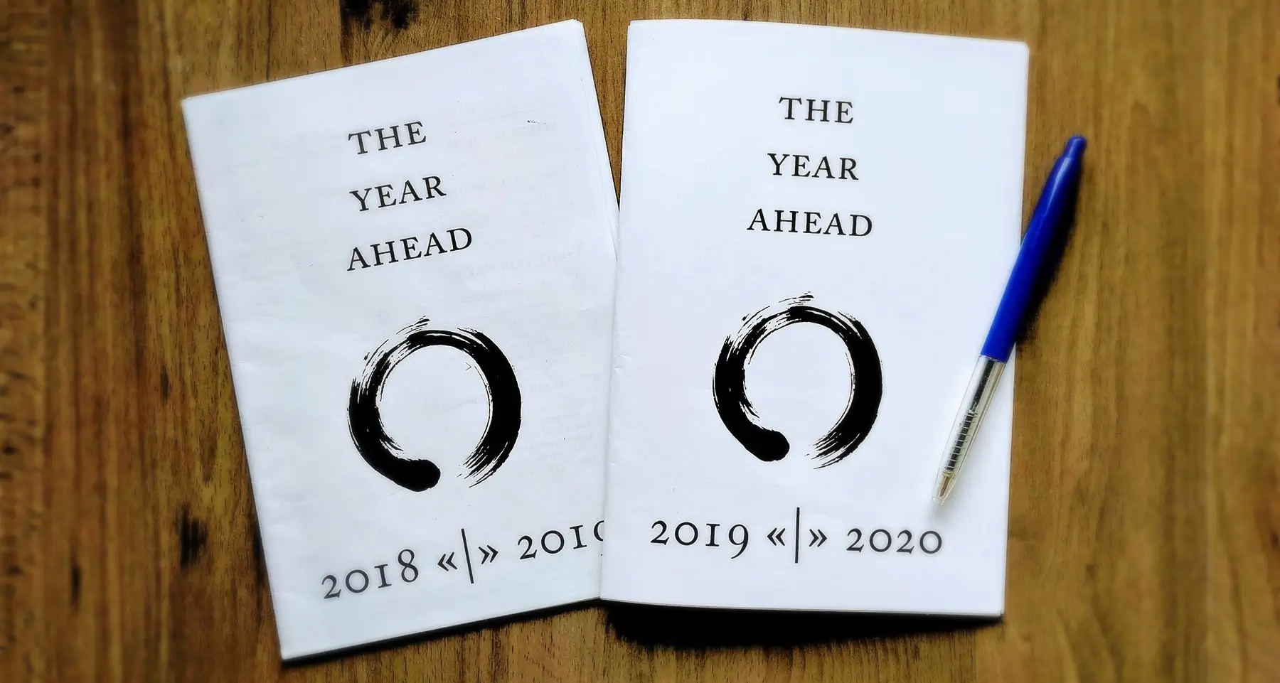 Two copies of 'The Year Ahead 2019 - 2020' lie on a table, with a blue pen.